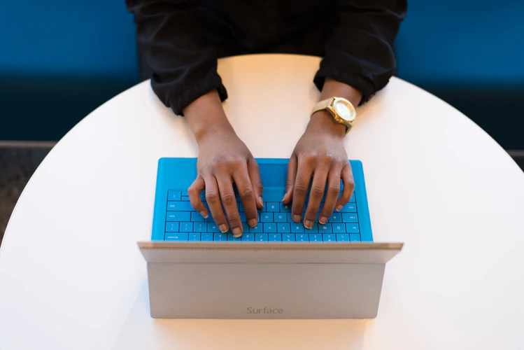 Employee types on blue keyboard Surface tablet
