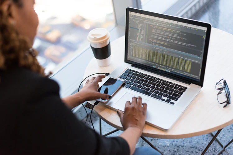 woman with coffee cup next to window with computer to show automation